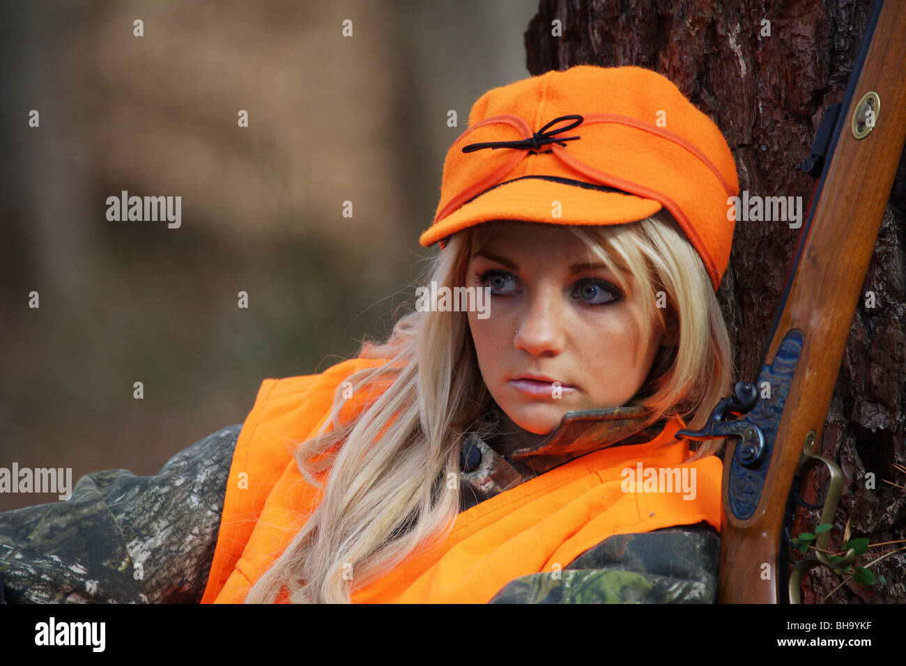 PORTRAIT YOUNG WOMAN 21 Y.O. FEMALE HUNTER IN FOREST WEARING ORANGE