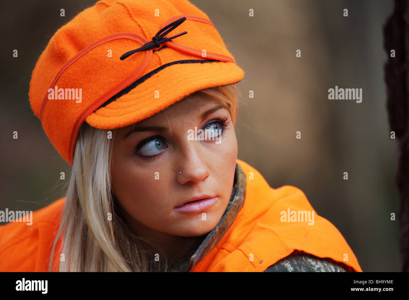 PORTRAIT YOUNG WOMAN 21 Y.O. FEMALE HUNTER IN FOREST WEARING ORANGE