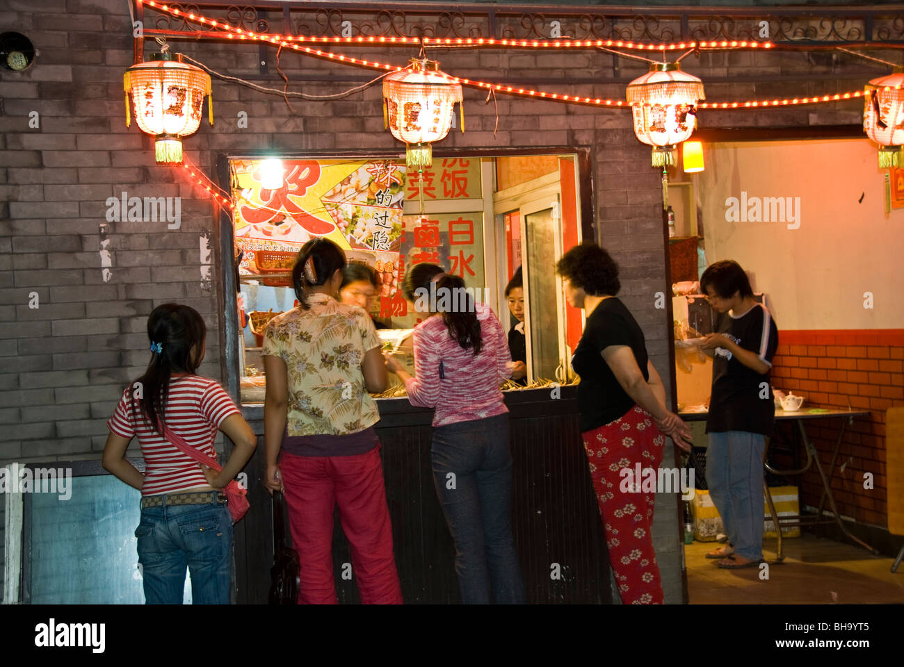 Beijing, CHINA- Old Traditional Hutong Neighborhood, Lit up at Night, Chinese Food Shop, late night food, shop window scene Stock Photo