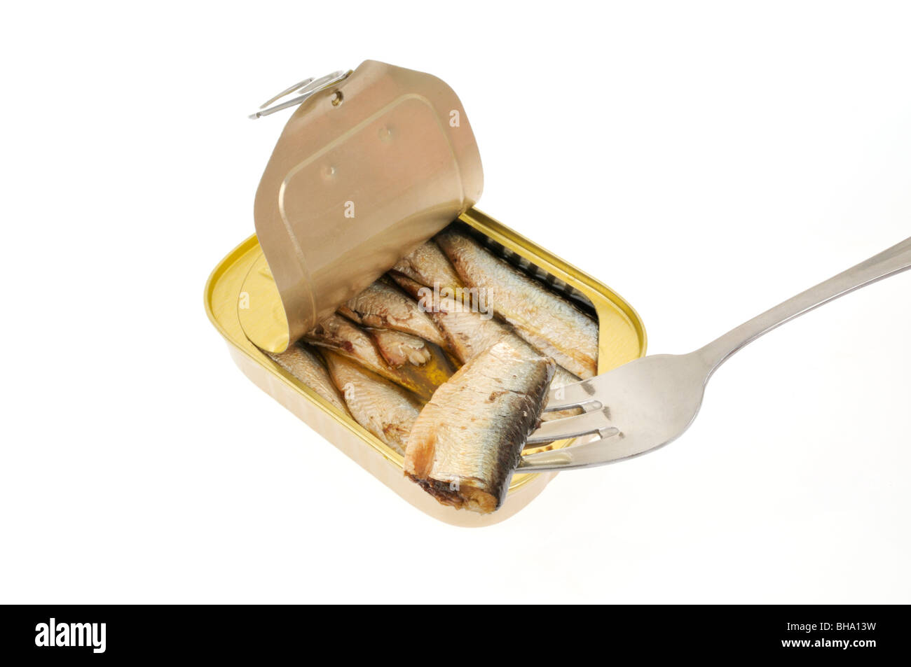 An open pull tab tin of sardines packed in oil on white background with a sardine on fork. Stock Photo
