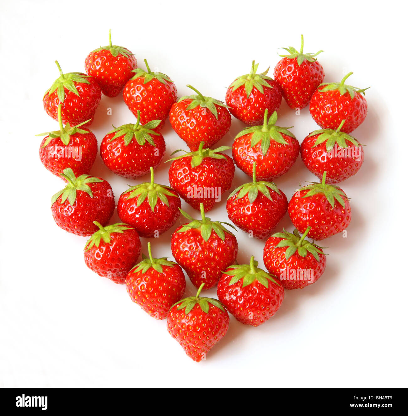 Fresh, ripe, organic strawberries placed to create a solid heart shape, on a white background. Stock Photo