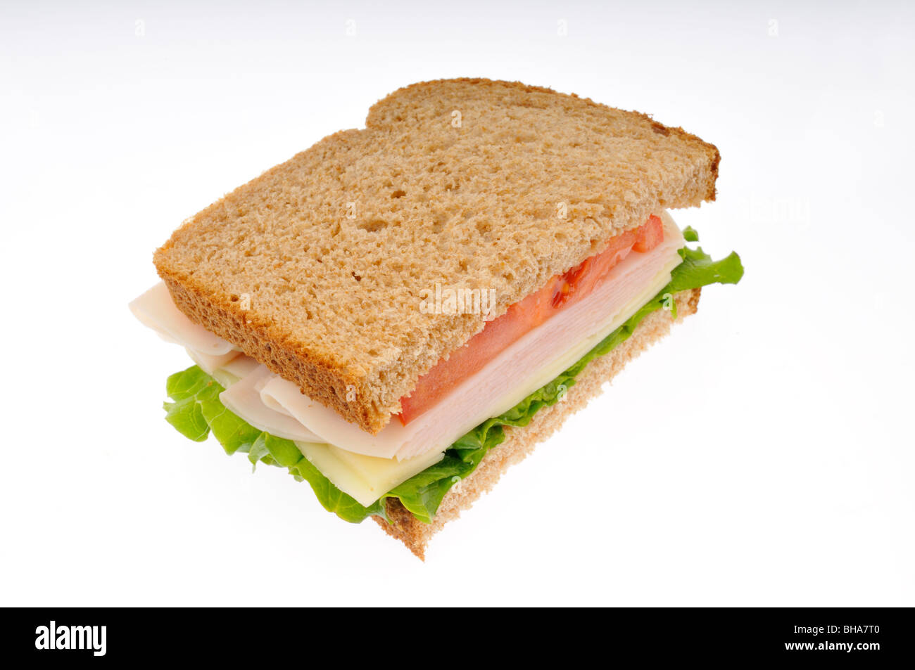 Half of turkey and cheese sandwich with lettuce and tomato on whole wheat bread stacked on white background. Cut out Stock Photo