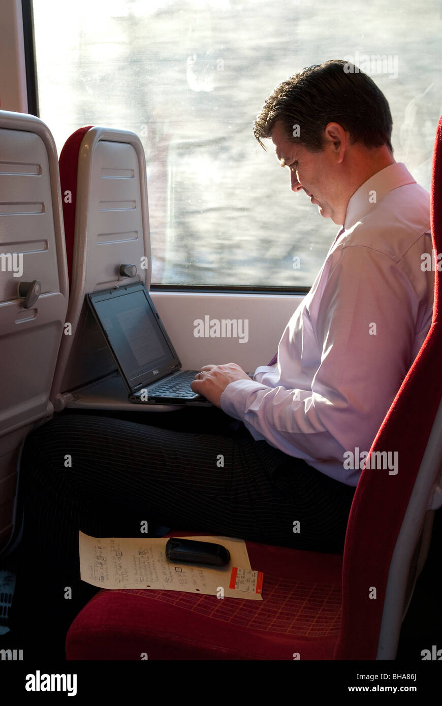 Business man commuter using laptop computer on passenger train journey Stock Photo