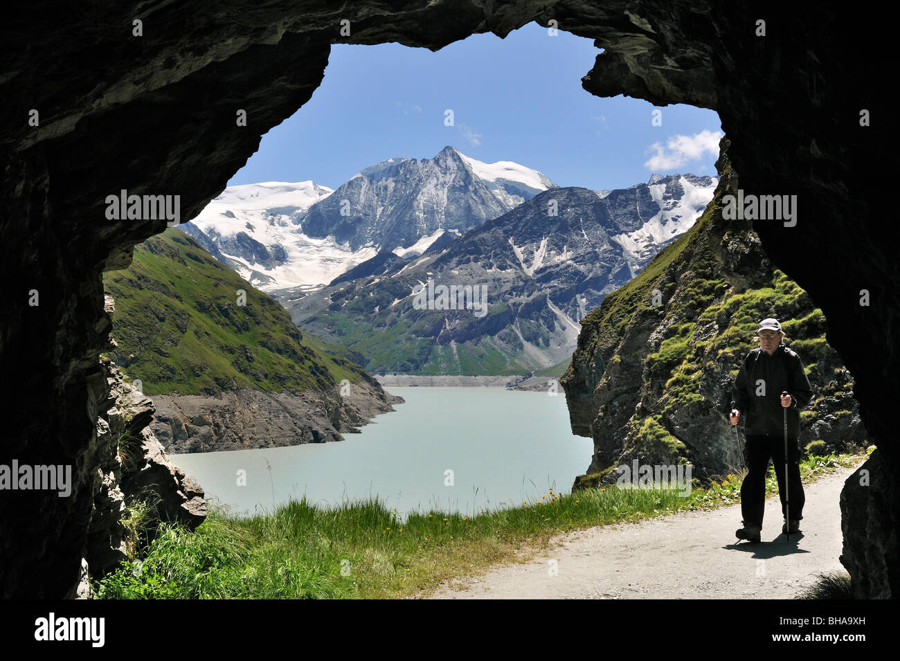 Tourist walking through cave along the Lac des Dix, formed by the Grande Dixence dam in Valais / Wallis, Swiss Alps, Switzerland Stock Photo