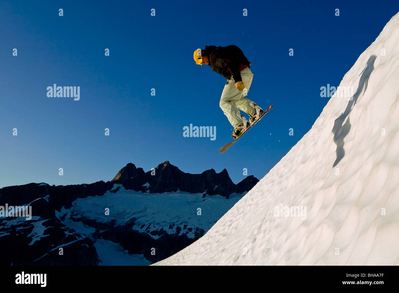 Snow boarder makes a jump on slopes in the Juneau area with Mendenhall Glacier and Towers in the background, southeast, Alaska Stock Photo