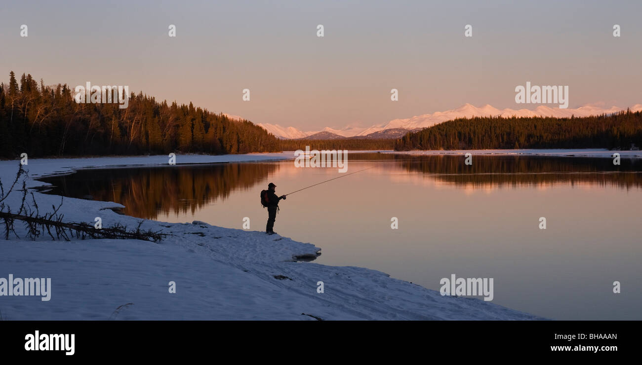 Lone fisherman fishing the Kenai River in Winter at Sunset Stock Photo