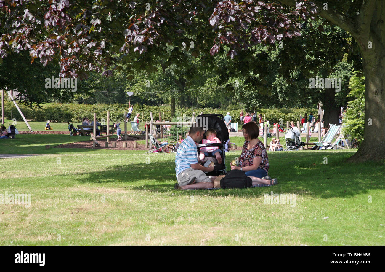A young couple with a small baby enjoying the sun at Trentham Gardens, Stoke-on-Trent, Staffs, England, UK Stock Photo
