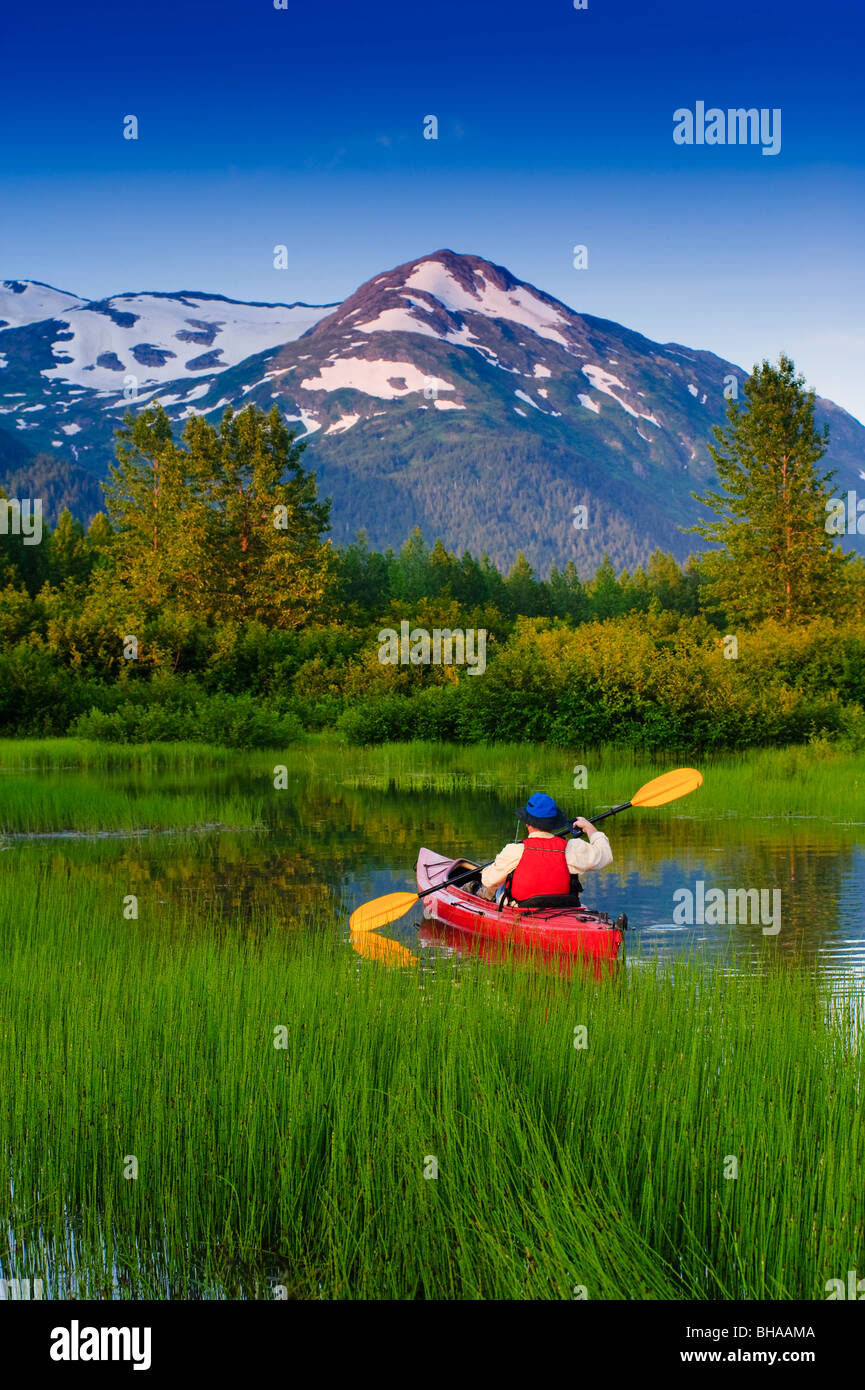 Man in a kayak paddling in a small lake in Portage Valley, Southcentral