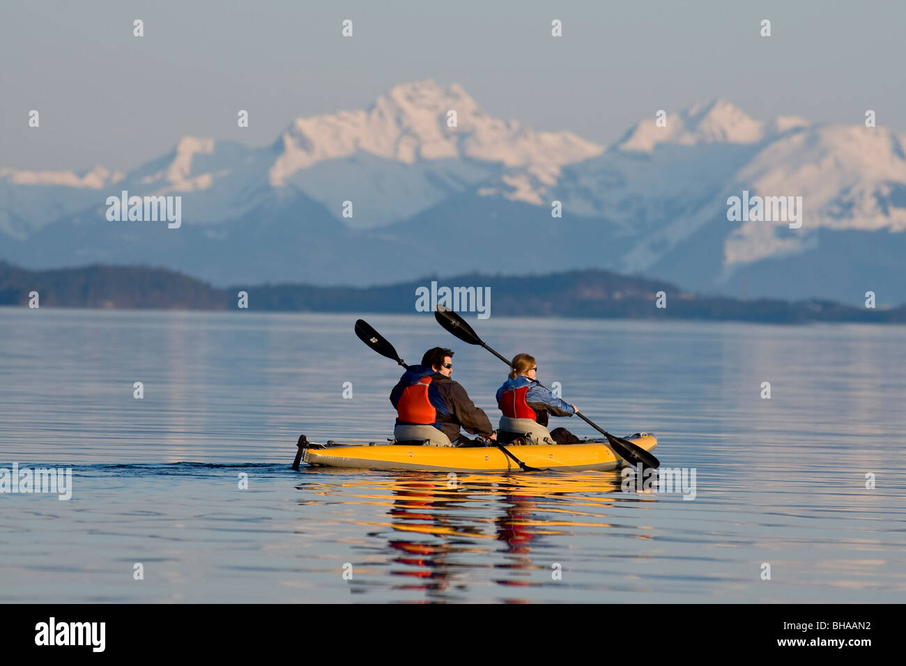 Sea Kayakers paddle the shoreline on a calm evening in Favorite Passage near Juneau, Alaska Stock Photo