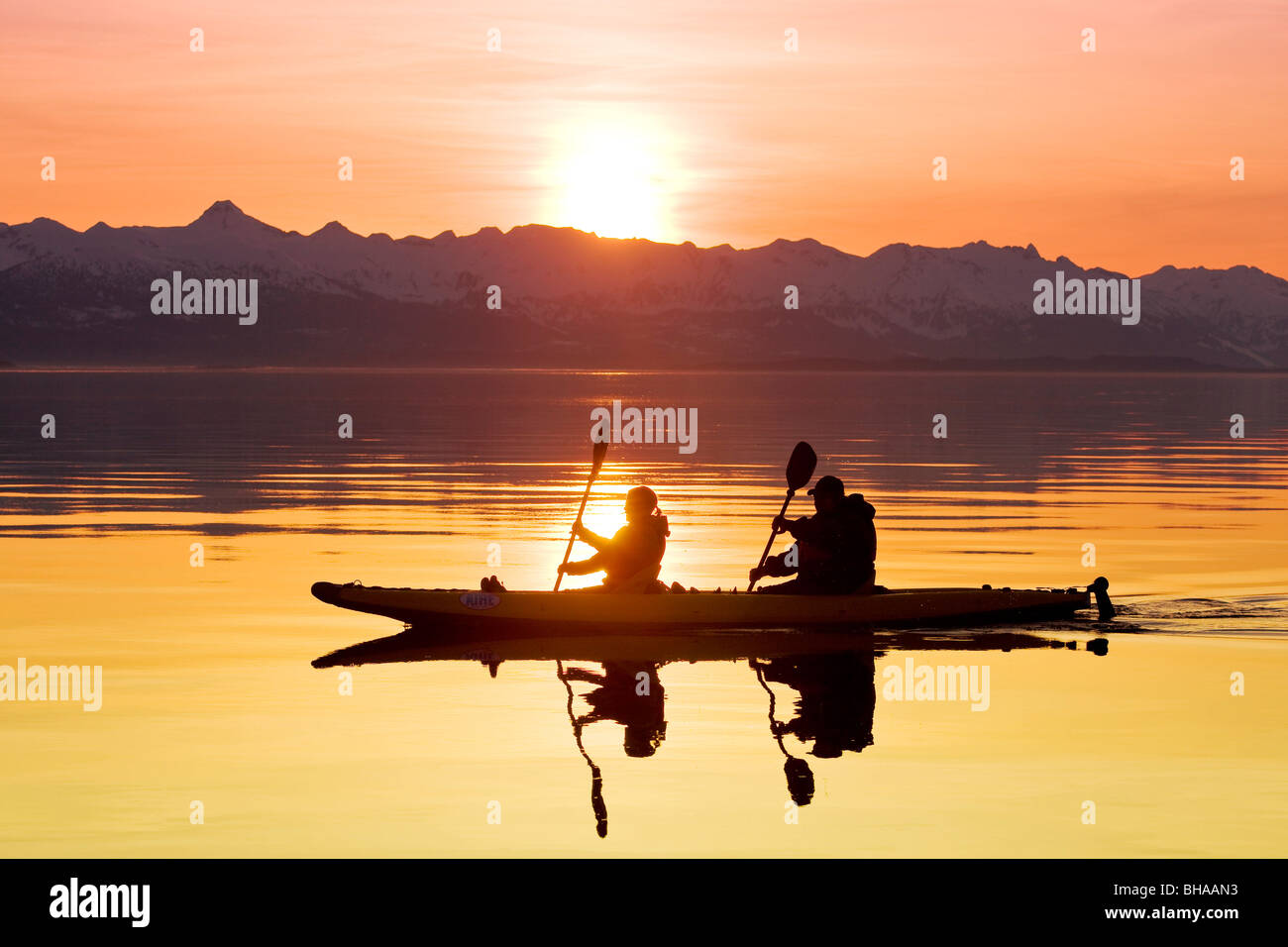 Kayakers paddle the calm waters of Alaska's Lynn Canal at sunset with the Chilkat Mountains in the background Stock Photo