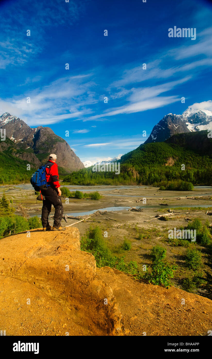 Hiker stands on a rock outcrop overlooking Eagle River, Chugach State Park, Southcentral Alaska, Summer Stock Photo