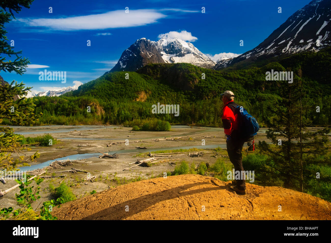 Hiker stands on a rock outcrop overlooking Eagle River, Chugach State Park, Southcentral Alaska, Summer Stock Photo