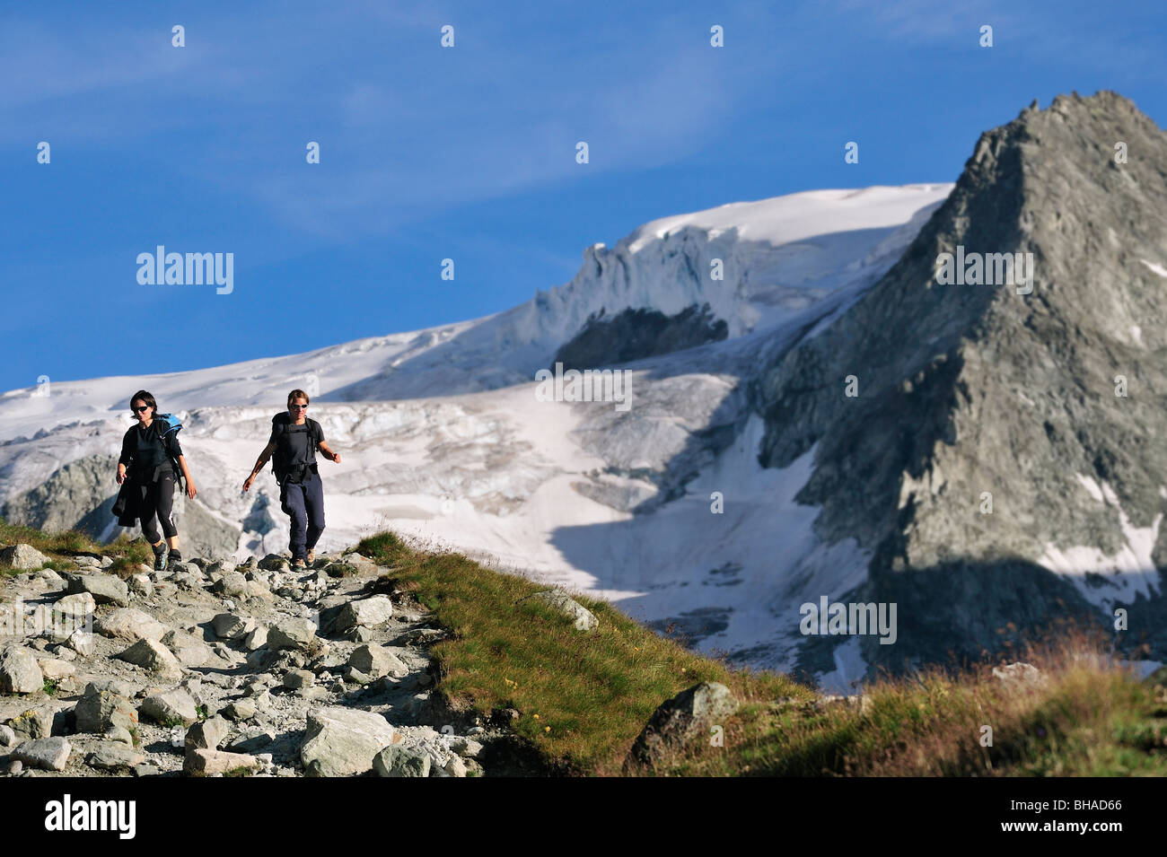 Two female hikers walking along mountain path in the Pennine Alps / Walliser Alpen, Valais / Wallis, Switzerland Stock Photo
