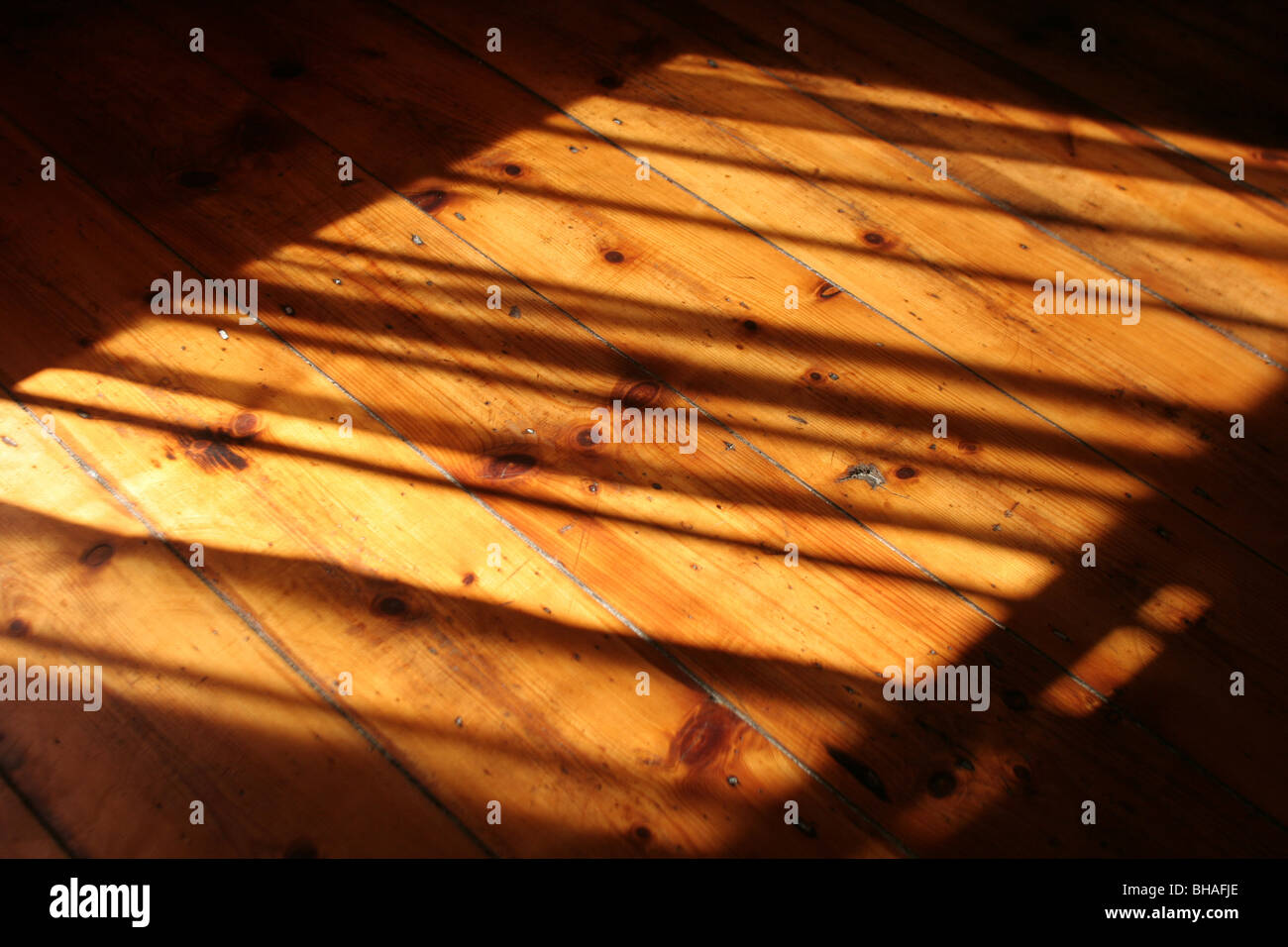 Sunlight falling on wooden polished floorboards, creating shadows Stock