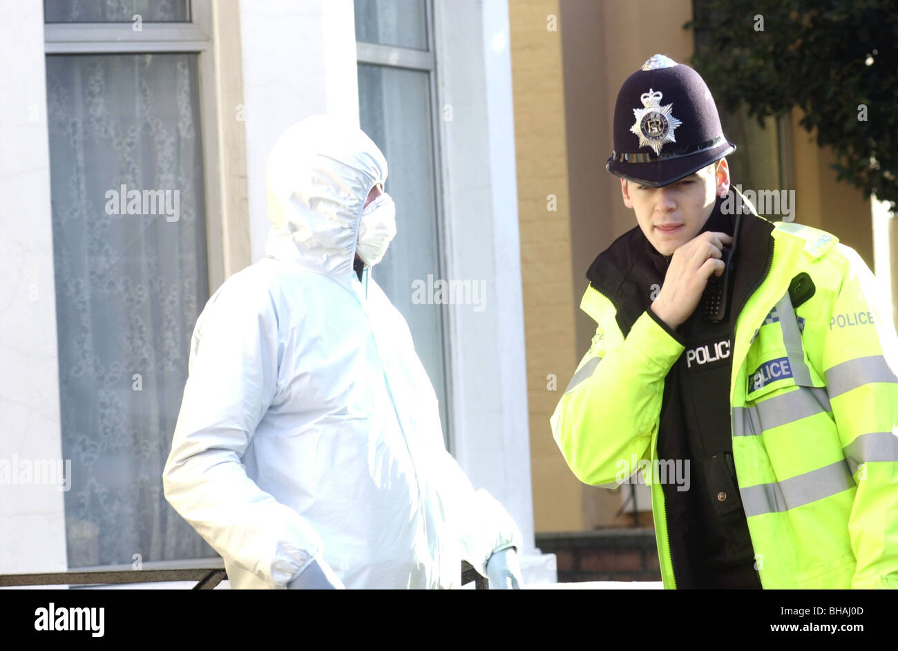 Scene of crime officer watches as a Police constable radios a message after a fatal attack UK. Stock Photo