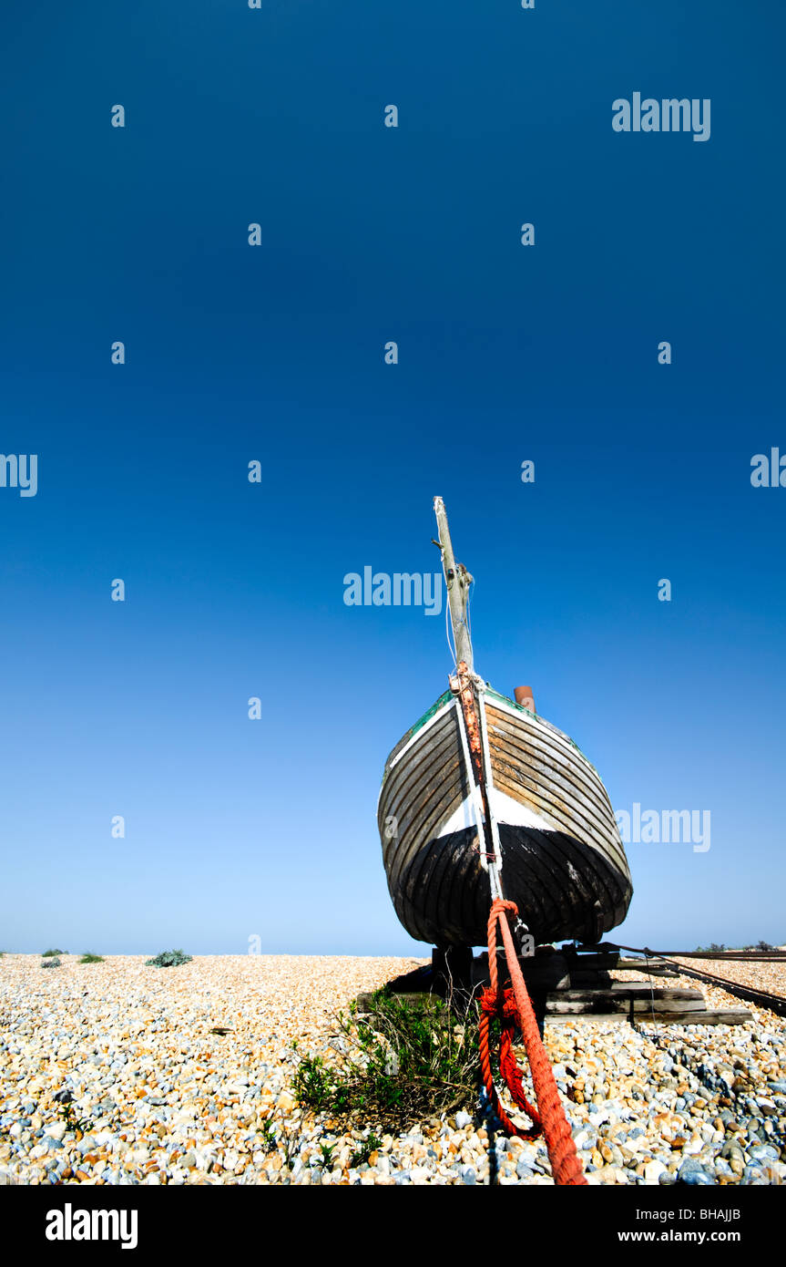 Old Fishing boat on pebble beach with clear blue sky and weed in the ...