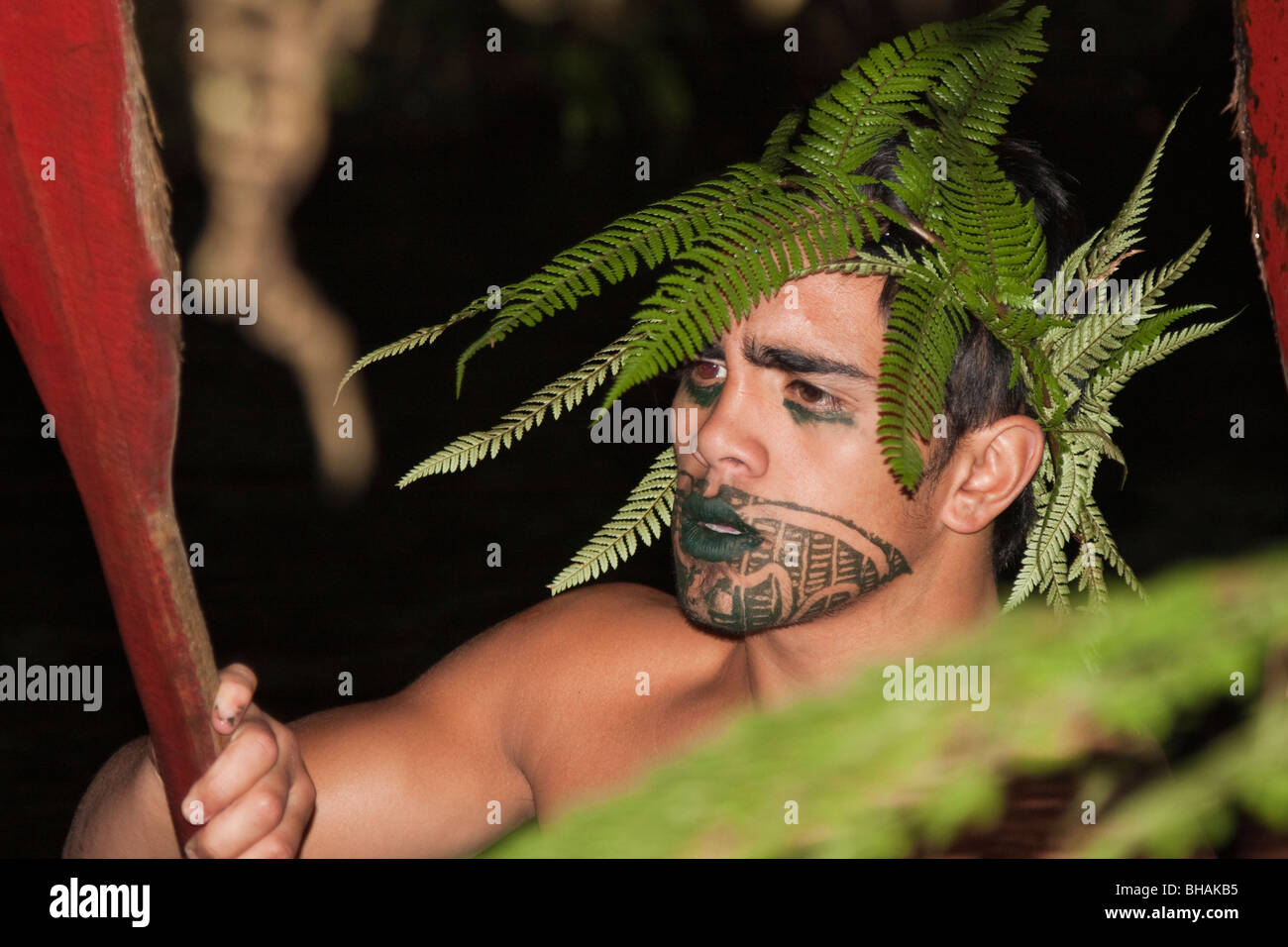 Maori oarsman wearing traditional clothing carrying an oar during cultural ceremony, Rotarua, North Island, New Zealand NZ Stock Photo