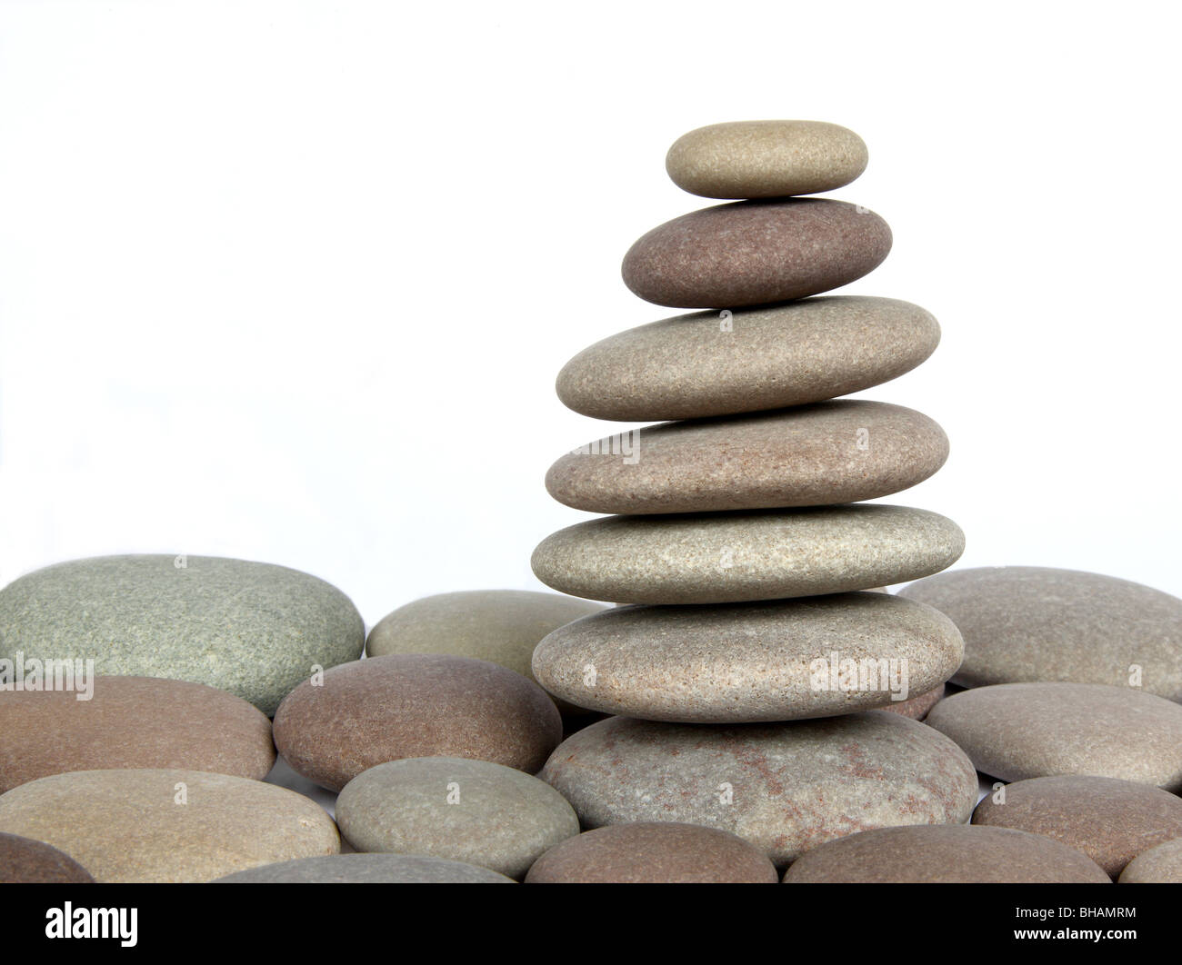 Stack of smooth, round granite pebbles on top of single pebbles, on white background. Stock Photo