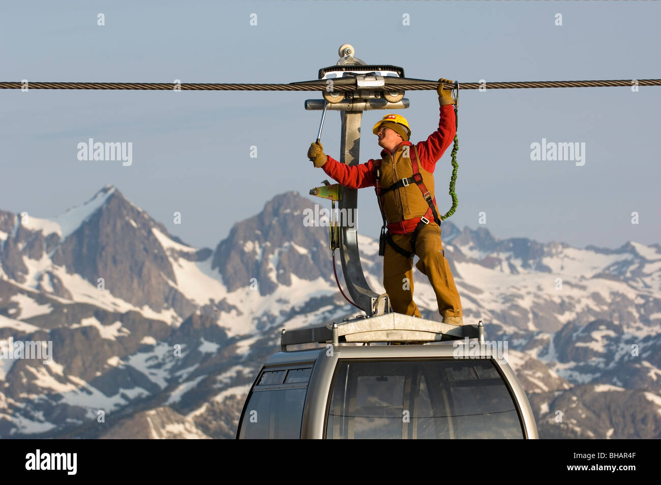 Ski resort workers working on top of a gondola with mountains and snow