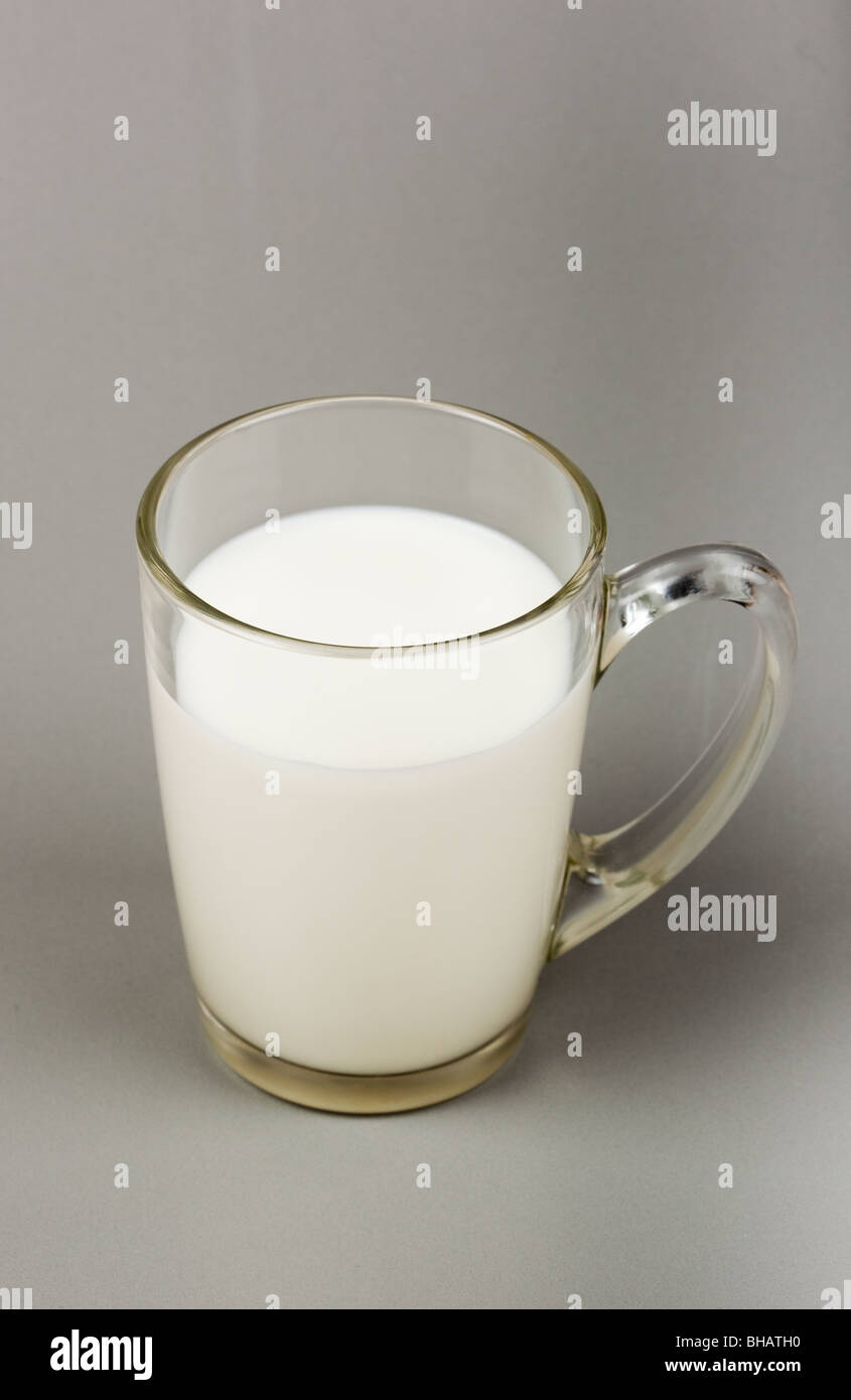 Transparent glass mug with milk on a grey background. Stock Photo