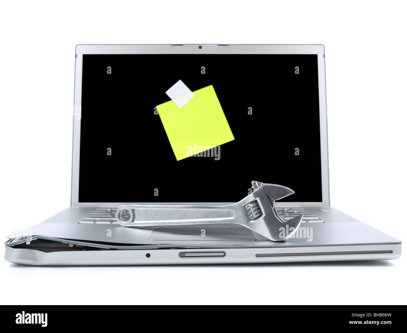 Damaged laptop with a spanner over it and a blank post-it on the screen. Isolated on white. Stock Photo