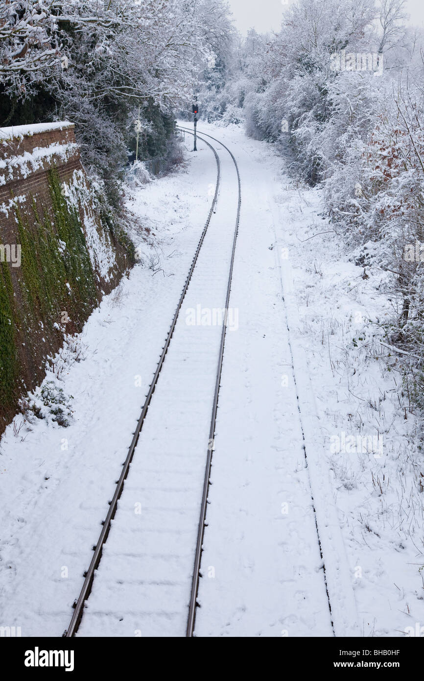 Snow covered railway tracks and a red stop light on a bend Stock Photo
