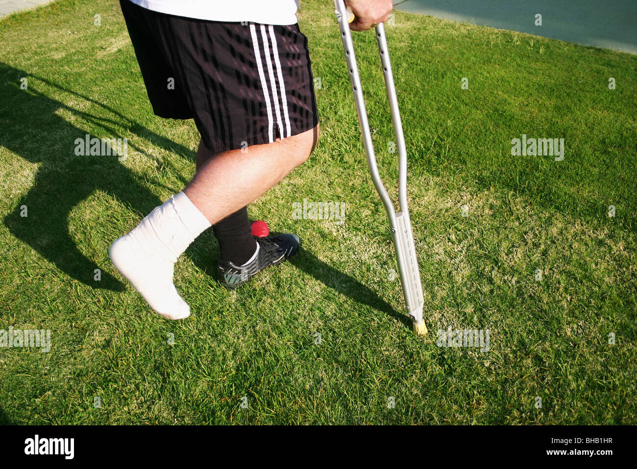 Footballer with ankle taped and bandaged limps away from pitch on