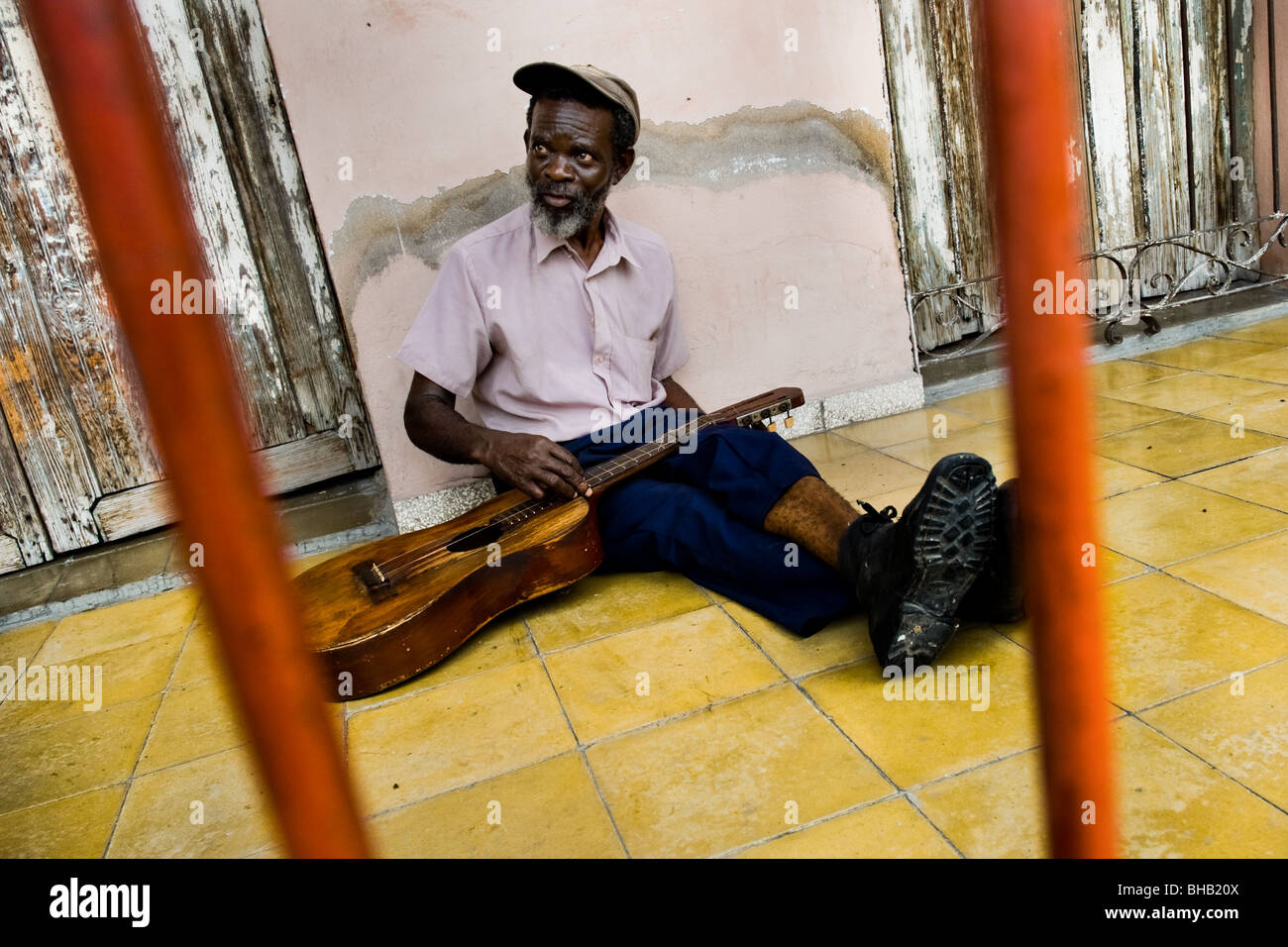 A Cuban musician (troubadour), changing strings on his old guitar during the Carnival in Santiago de Cuba, Cuba. Stock Photo