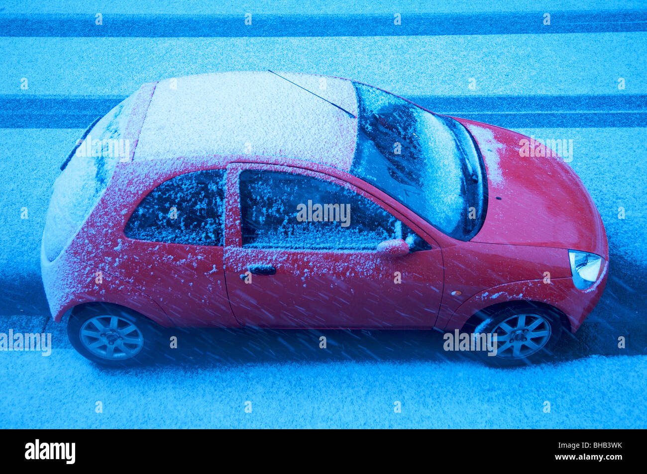 Red car parked in street in snow Stock Photo