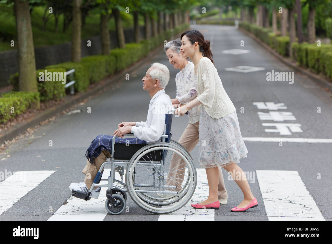 Japan, Tokyo Prefecture, Woman pushing senior man in wheelchair
