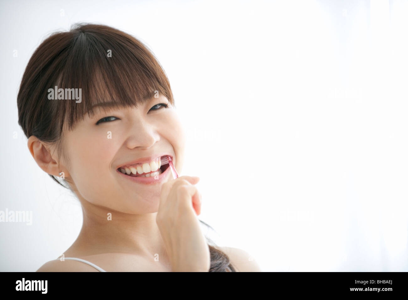 Japan, Osaka Prefecture, Woman brushing teeth, smiling, portrait Stock Photo