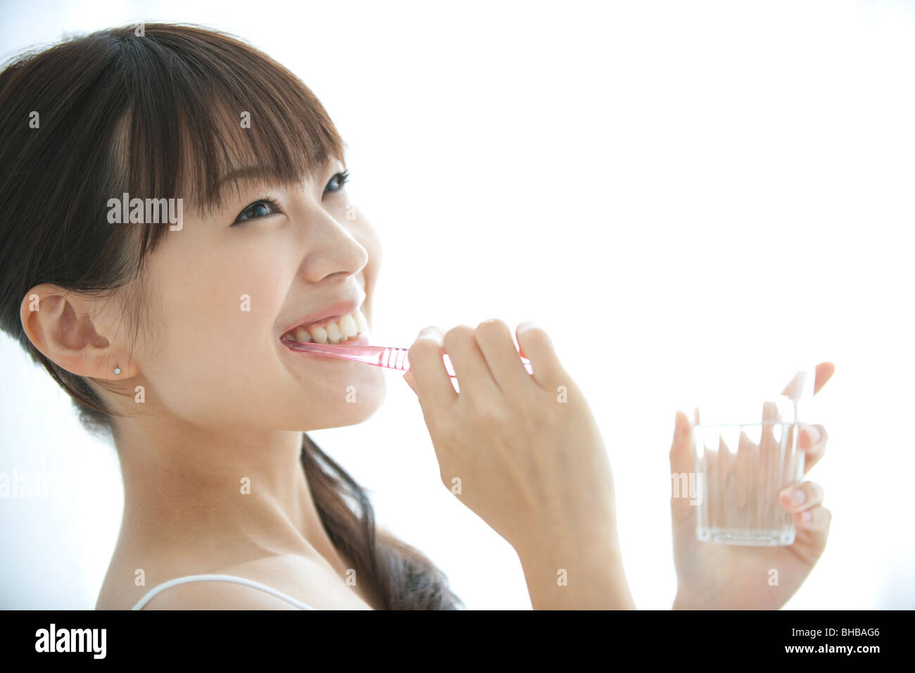 Japan, Osaka Prefecture, Woman brushing teeth, smiling, close-up Stock Photo