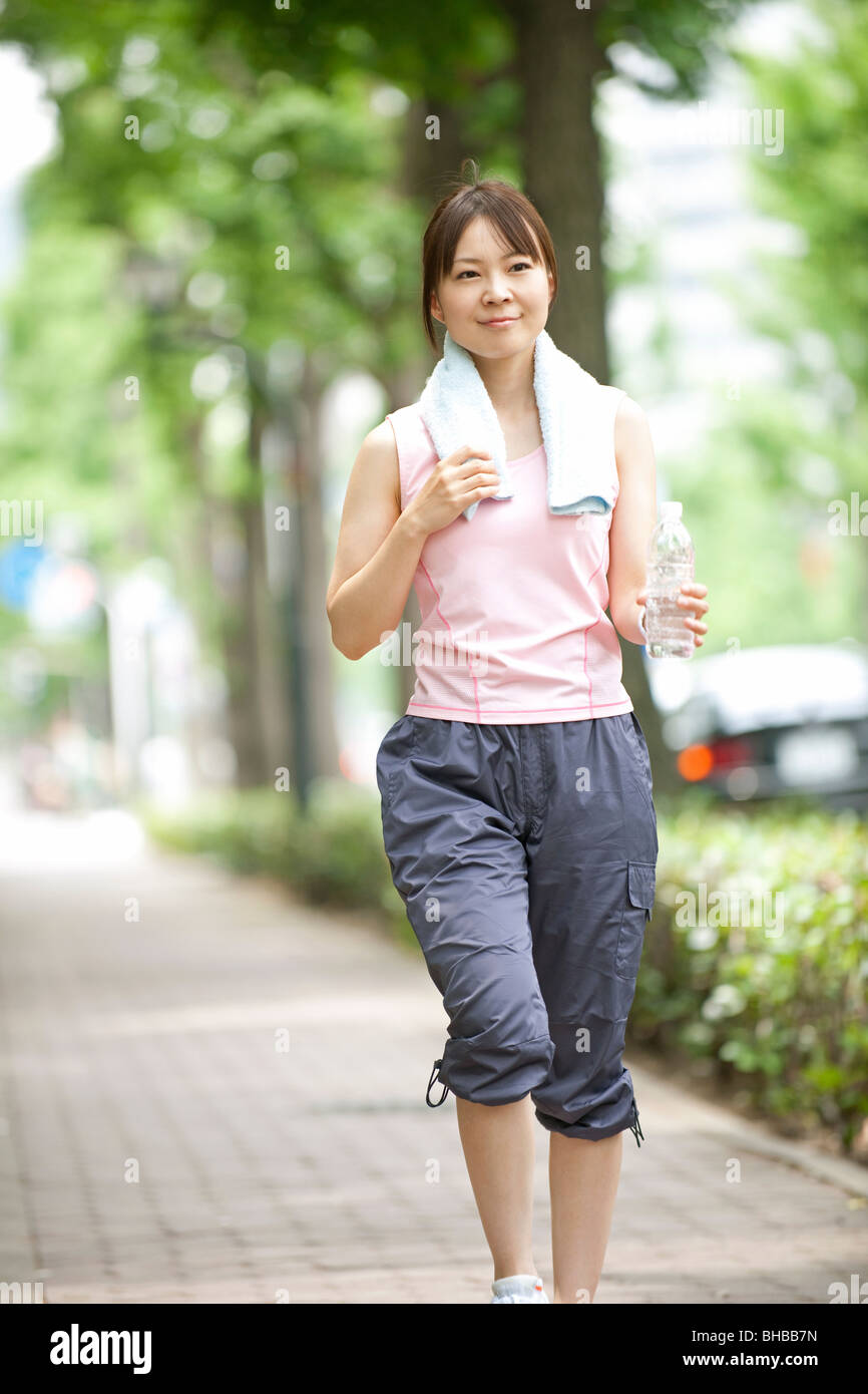 Japan, Osaka Prefecture, Woman walking on path, smiling Stock Photo
