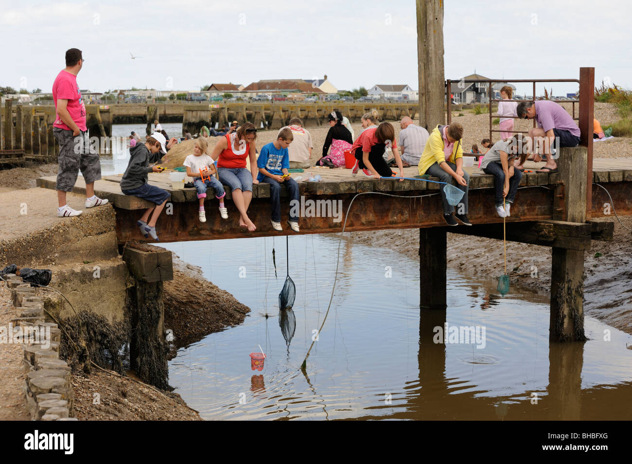 Fishing for crabs from wooden bridge at Walberswick beach,Suffolk,UK