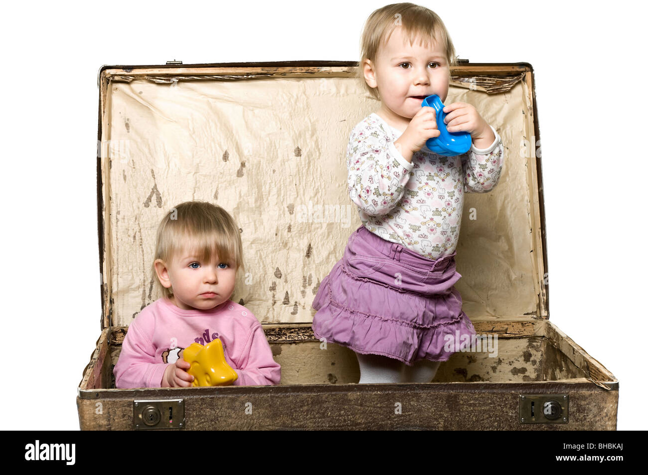 Two little babies playing in suitcase. Sitting inside. Isolated over