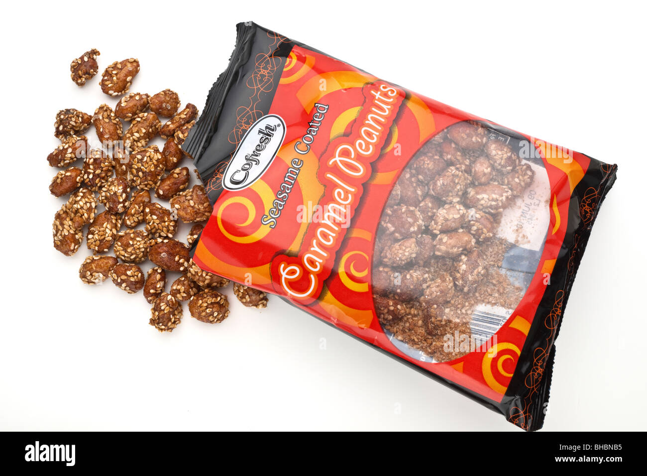 Bag of Cofresh Sesame coated caramel peanuts spilling onto a white surface Stock Photo