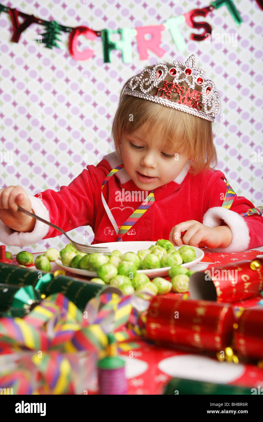A three year old sitting at a table with Christmas decorations and a