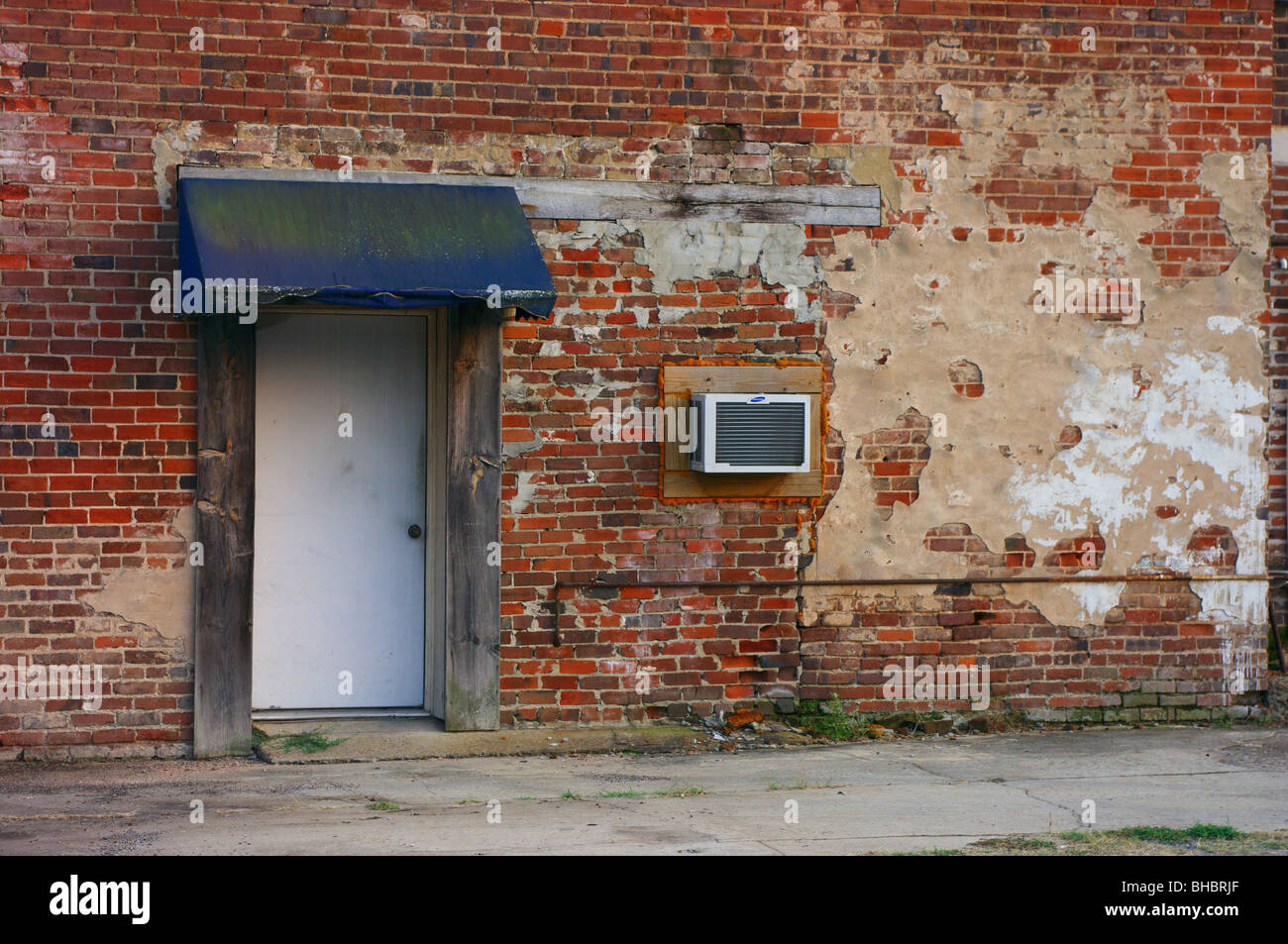 Old brick wall with door, awning and window air conditioner Stock Photo