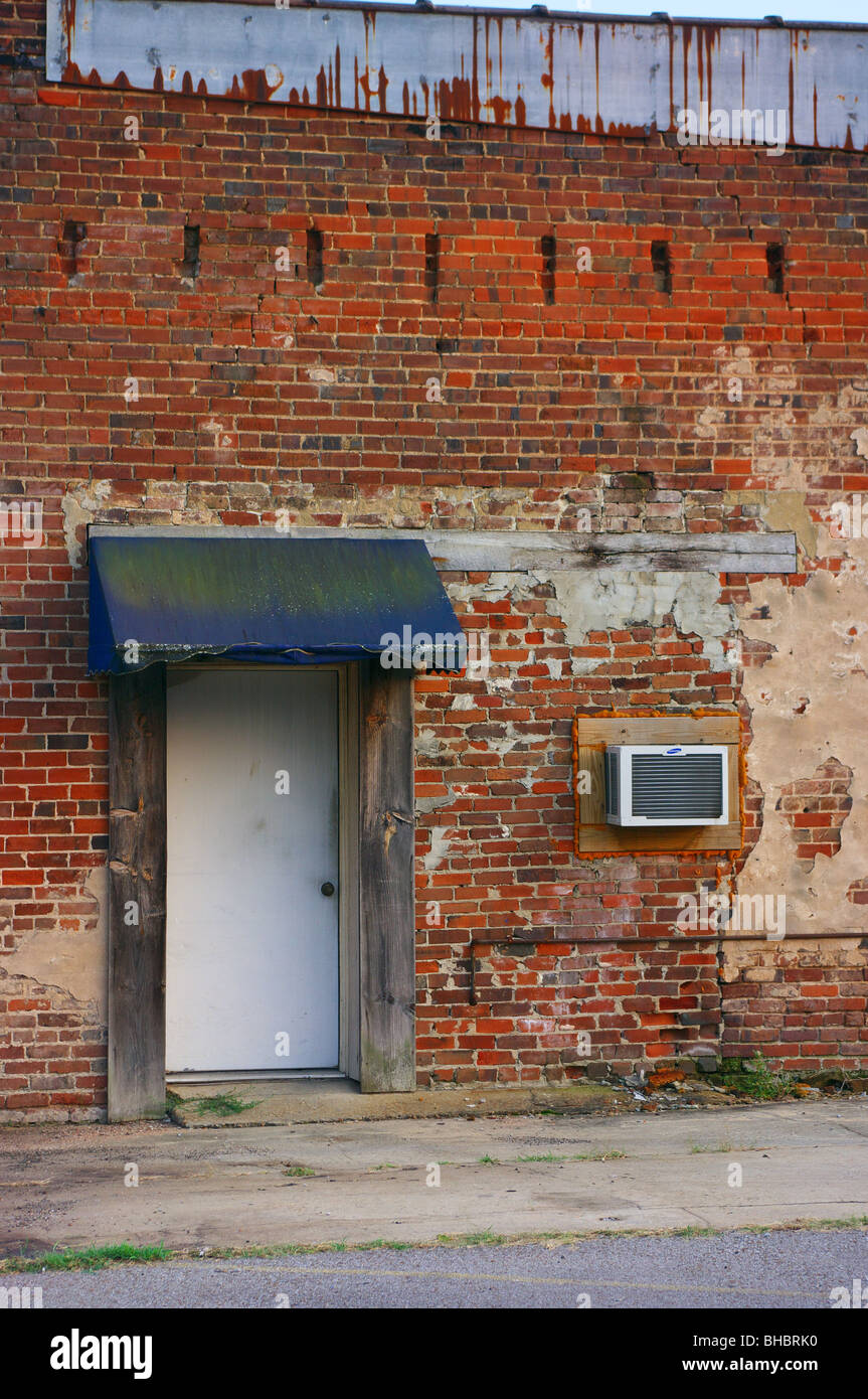 Old brick wall with door, awning and window air conditioner Stock Photo