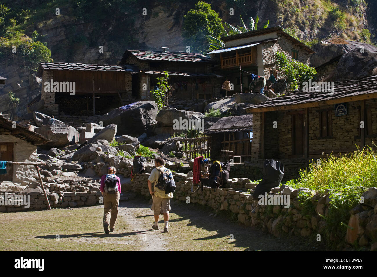 Trekkers enter a village in the Budhi Gandaki gorge - AROUND MANASLU TREK, NEPAL Stock Photo
