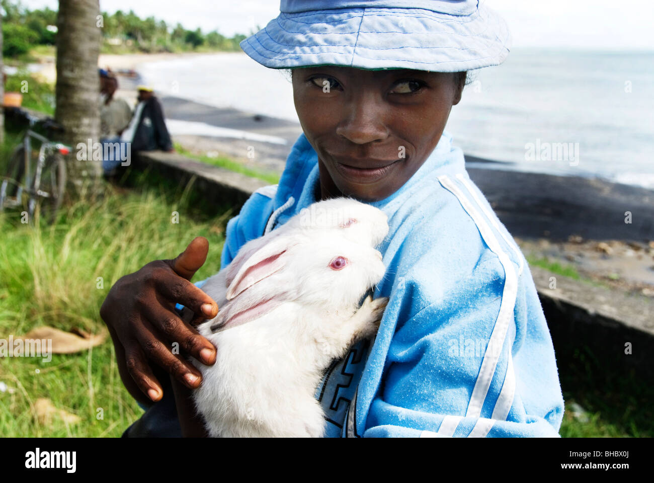 Madagascar January 2010 Young woman holding two rabbits by the sea ...