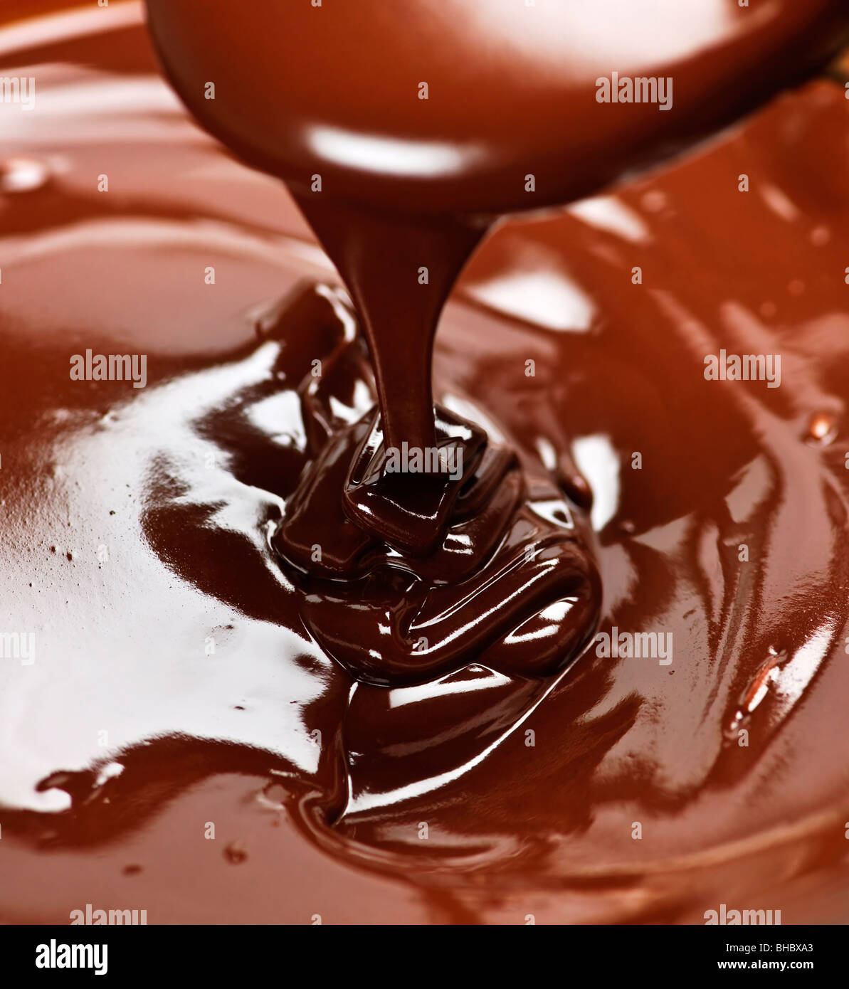 Melted rich dark chocolate dripping from spoon Stock Photo