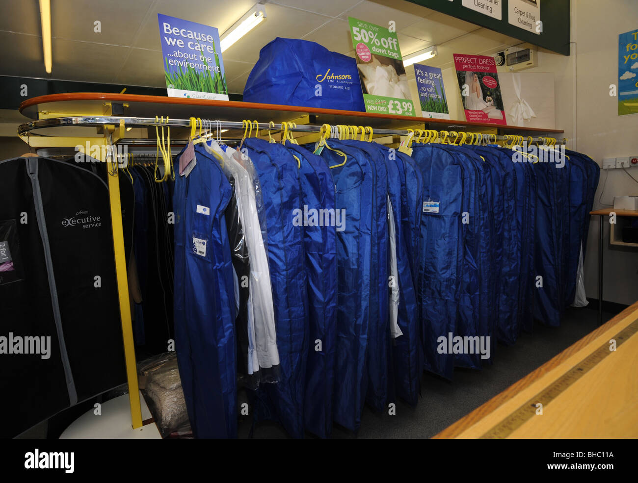 Dry cleaned clothes waiting for collection in a branch of johnson the dry cleaners Stock Photo
