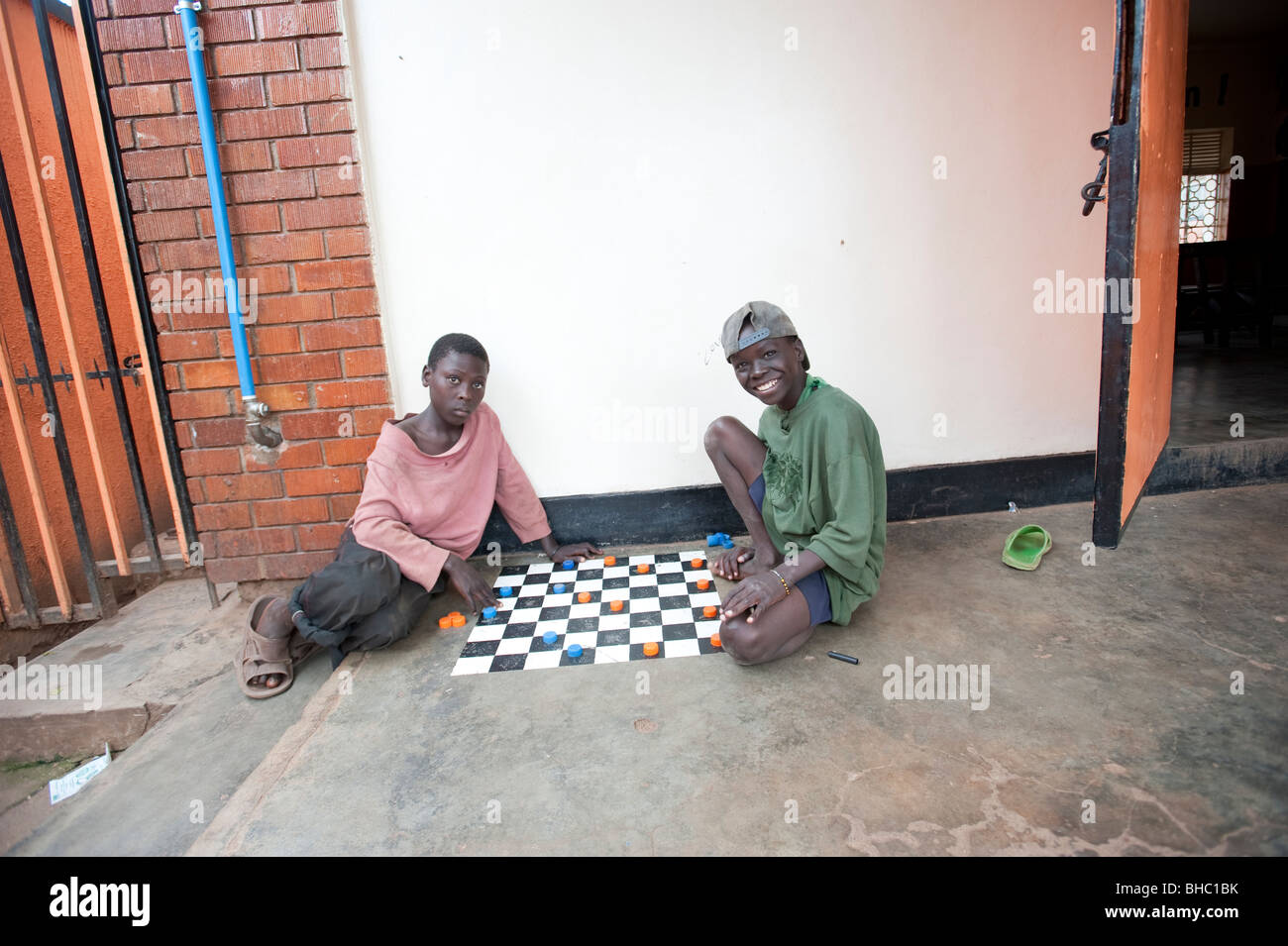 Two homeless boys playing draughts in centre, Kampala Uganda Stock Photo