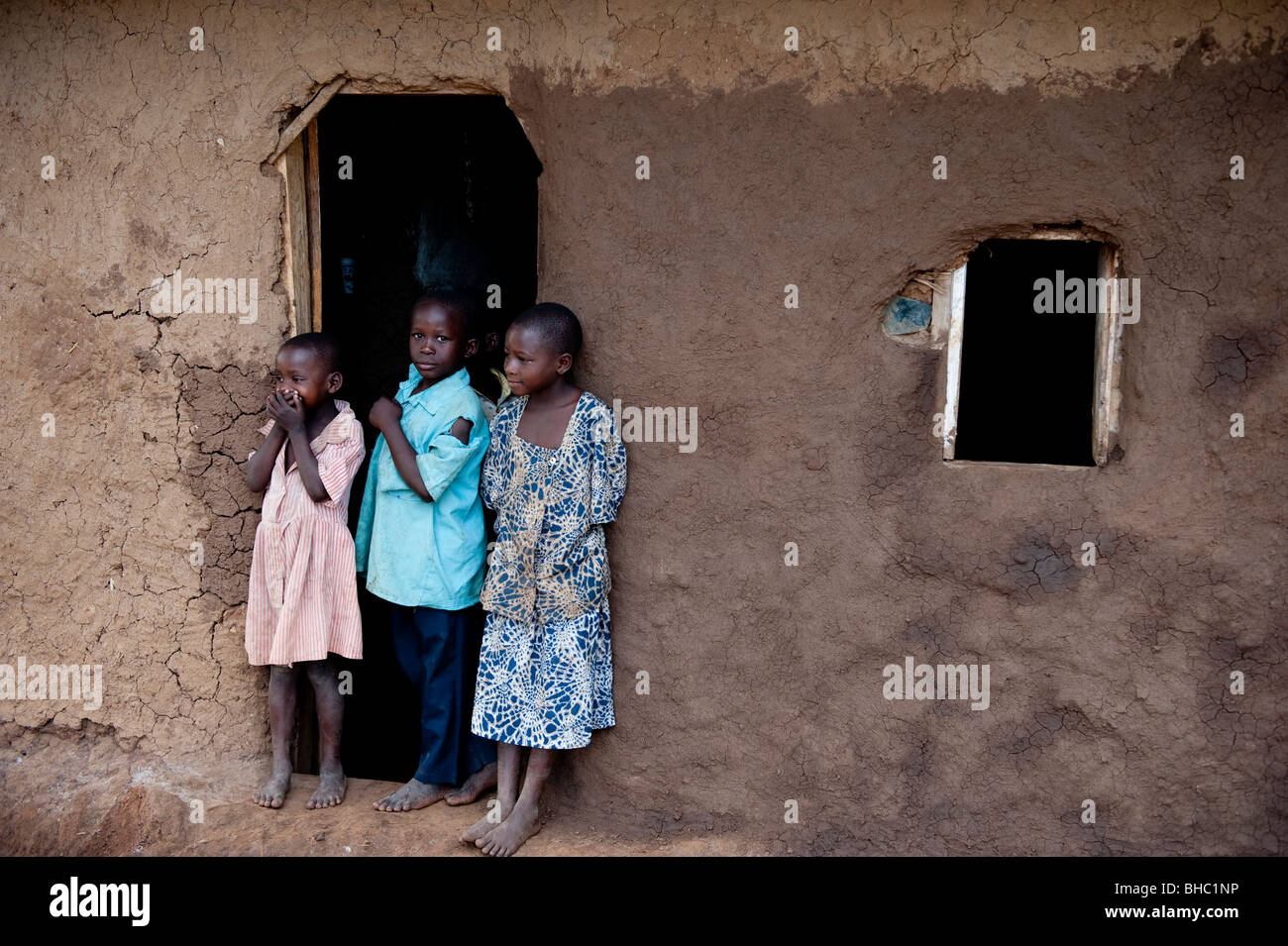 Three children outside traditional homestead in Hoima Uganda Africa Stock Photo