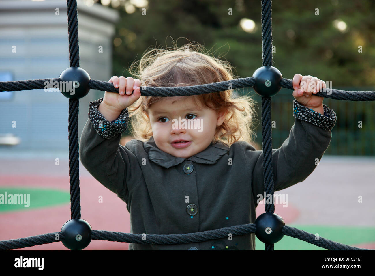 A twenty months old baby girl playing on a slide into a public garden Stock Photo