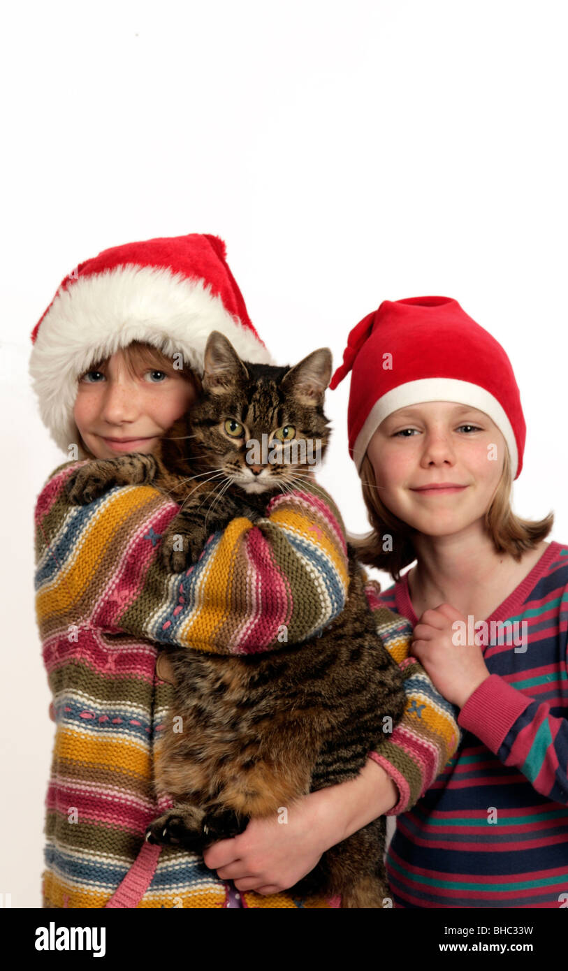 two girls in santa hats holding their tabby cat. A pet is for life, not for christmas Stock Photo
