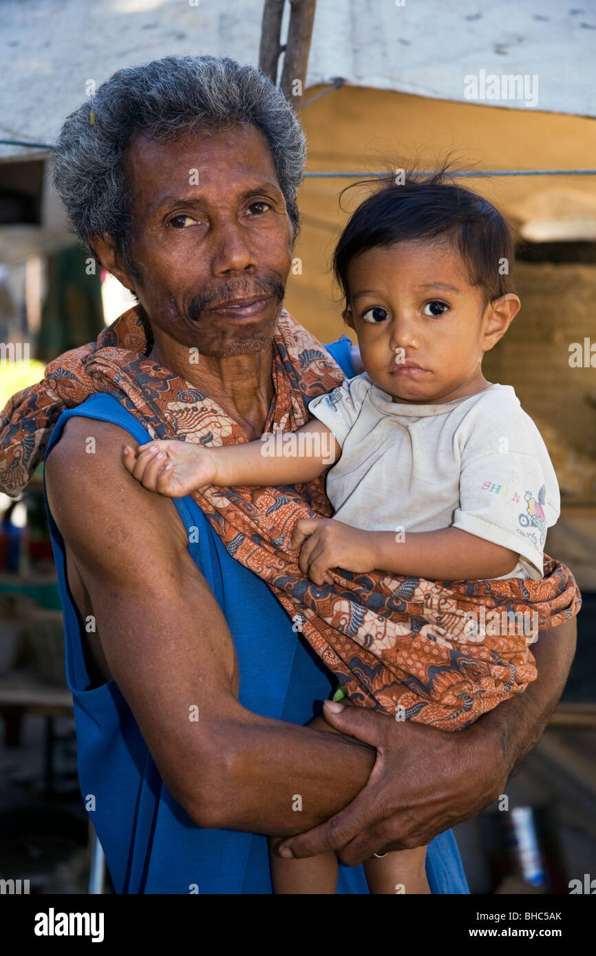 Caring Grandfather carpenter looks after his grandchild at IDP camp for displaced homeless people in Dili East Timor Stock Photo