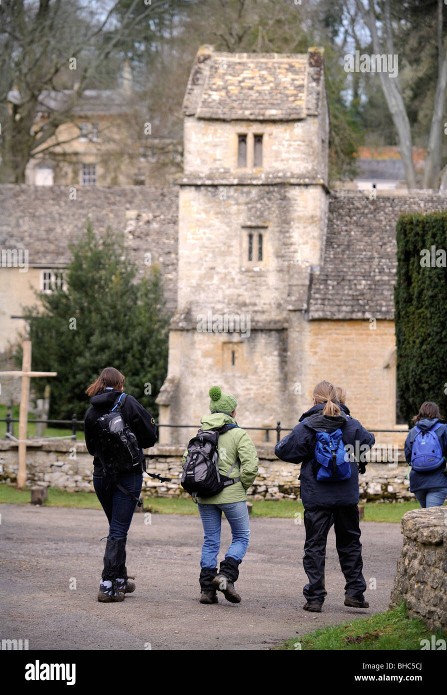 A group of walkers pass St Margaret's Church, Bagendon Gloucestershire UK Stock Photo
