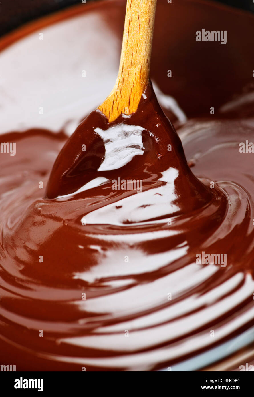 Wooden spoon stirring soft melted rich chocolate Stock Photo
